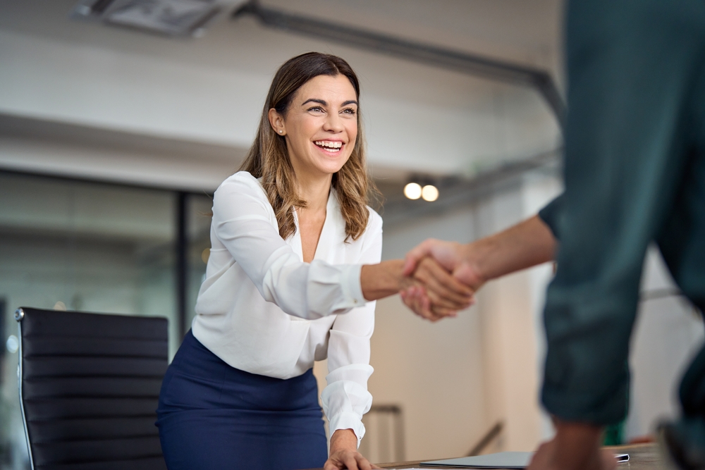 Happy,mid,aged,business,woman,manager,handshaking,greeting,client,in - What’s Missing from Today’s Onboarding Programs?